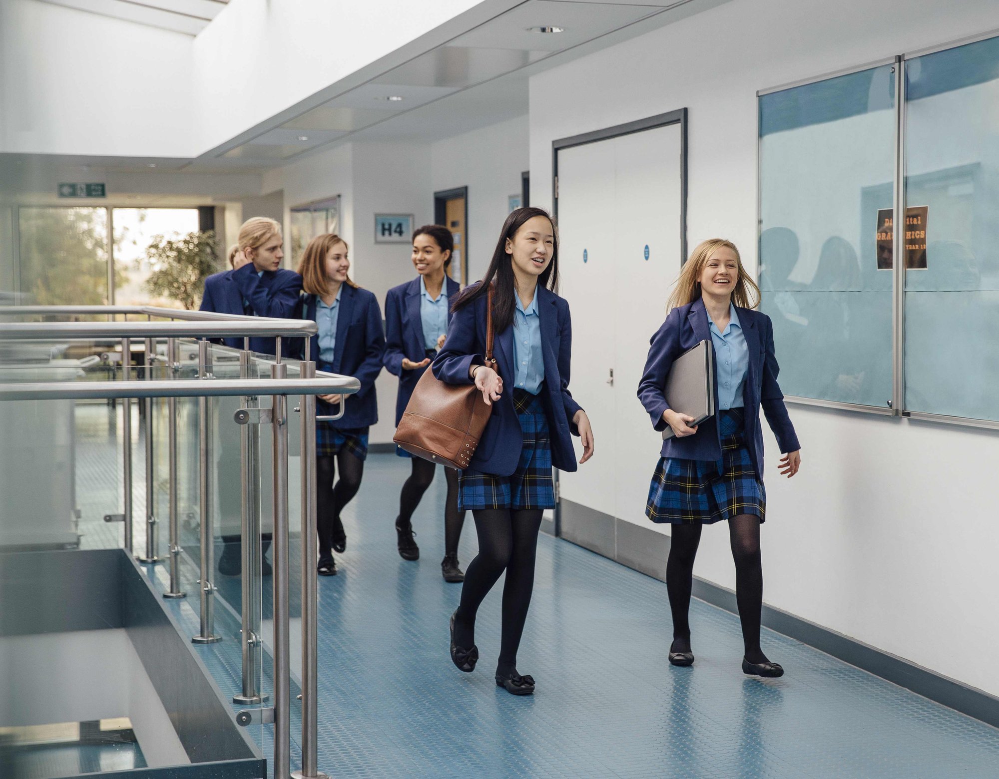 Pupils in school uniforms walking through school building