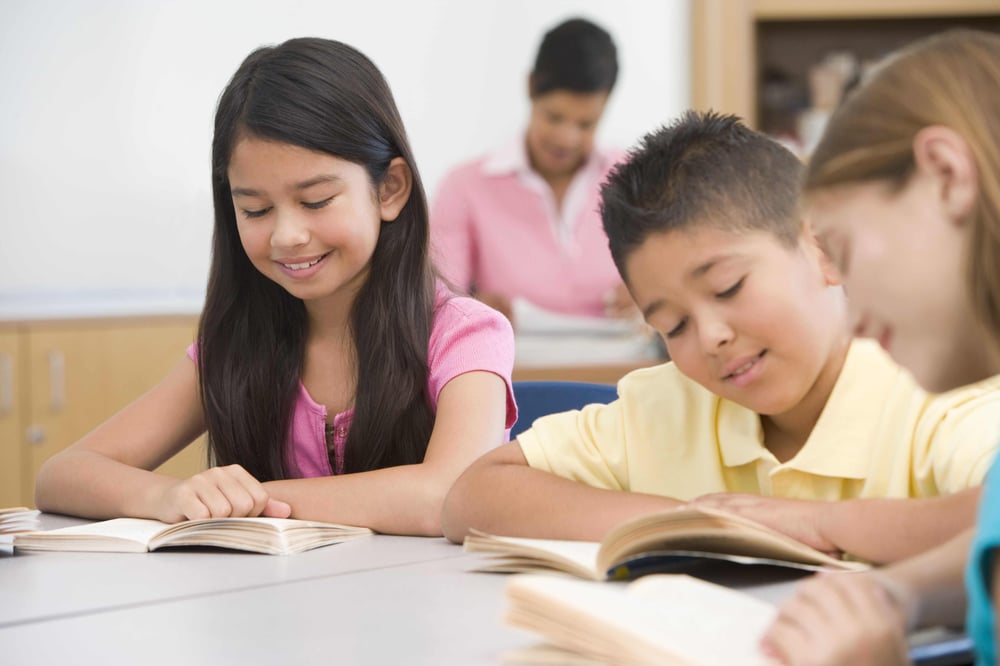 School pupils in classroom reading together happily