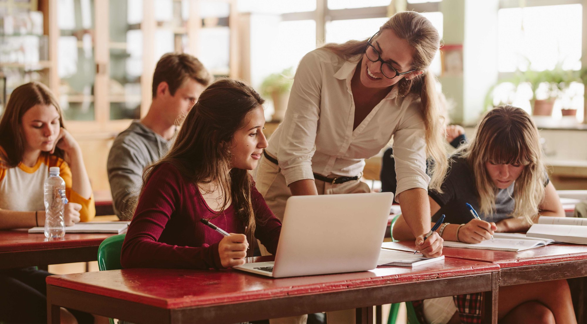 Tutor advising student on requested study materials in classroom