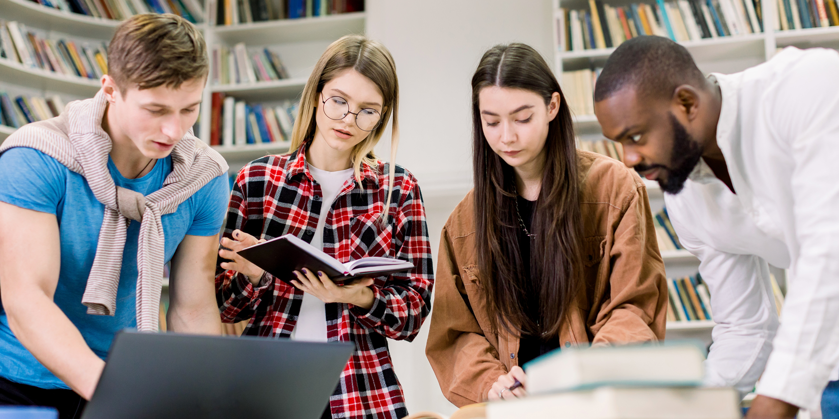 college students working in library around laptop